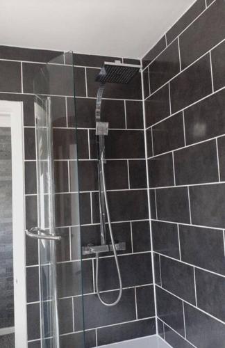 a shower in a bathroom with black tiles at Alexandra place Skipton child and dog friendly in Skipton
