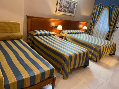 a hotel room with three beds with blue and yellow stripes at Hotel Niagara in Catanzaro Lido