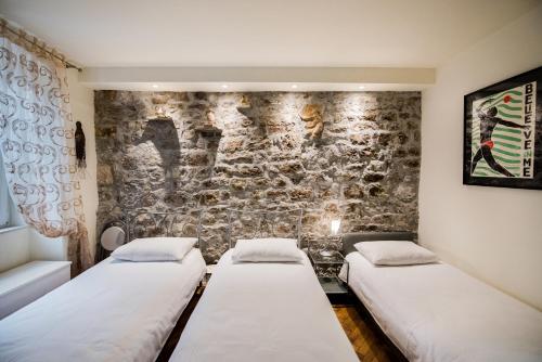 Dos camas en una habitación con pared de piedra. en Diocletians Heart Apartment, en Split