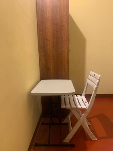 a white desk and a chair sitting next to a wall at Cafe Sola bnb in Shillong