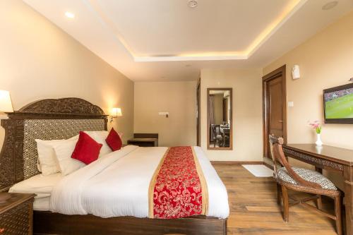 a bedroom with a bed and a desk and a television at Himalayan Ghar in Kathmandu