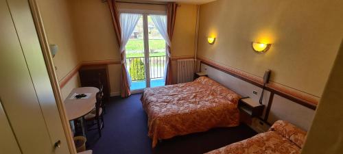 a hotel room with two beds and a window at Le VAL du CANTAL in Polminhac