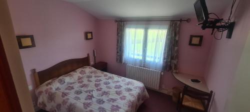 1 dormitorio con cama, escritorio y ventana en Le VAL du CANTAL, en Polminhac