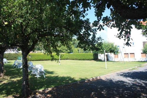 a park with two chairs in the shade of a tree at Le VAL du CANTAL in Polminhac