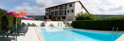 een hotel met een zwembad met stoelen en een parasol bij Le VAL du CANTAL in Polminhac