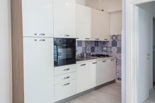 una cocina con armarios blancos y un aparato negro en A casa di Marica, en Sirolo