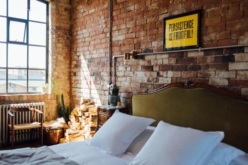 um quarto com uma cama e uma parede de tijolos em Destinesia Jason Works em Loughborough