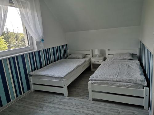 two twin beds in a room with a window at Domki Białogóra in Białogóra