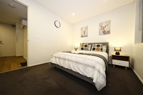1 dormitorio con 1 cama y reloj en la pared en Superb 1 bed apartment in Syd CBD Darling Harbour, en Sídney