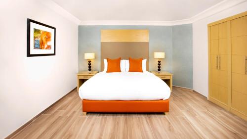 a bedroom with a large bed with orange pillows at Mövenpick Resort Petra in Wadi Musa
