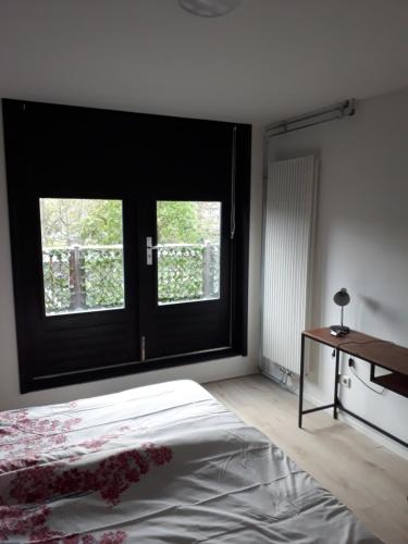 1 dormitorio con puerta negra, cama y escritorio en janneke, en Egmond aan Zee