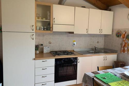 a kitchen with white cabinets and a sink and a stove at La Terrazza sulle Apuane in Fivizzano