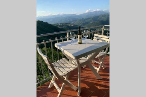 a white table and chairs on a balcony with a bottle of wine at La Terrazza sulle Apuane in Fivizzano