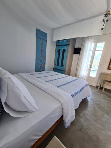 a bedroom with a large white bed with a blue headboard at Amfitriti Serifos in Livadion