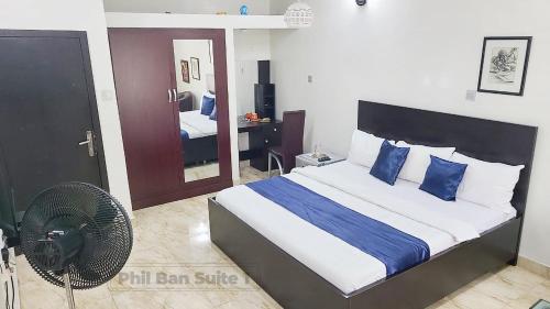 a bedroom with a bed with blue pillows and a fan at PhilBan Suites 1 in Ikeja