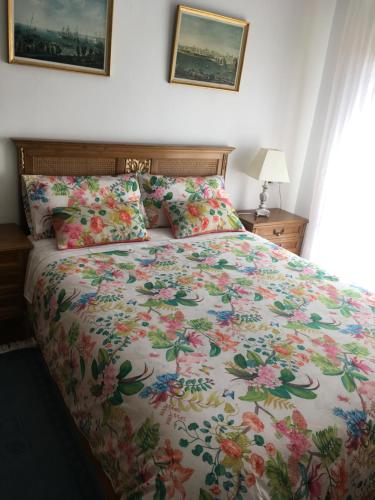 uma cama com uma colcha floral e almofadas em Saldaña. Apartamento em Saldaña