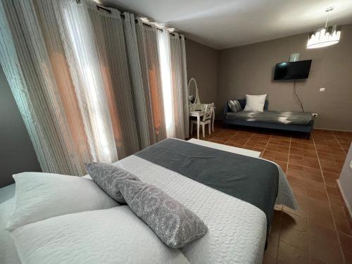 a bedroom with a bed and a couch and a television at Hostal EL GRIEL NO DISPONEMOS DE RECEPCIÓN FÍSICA in Hervás