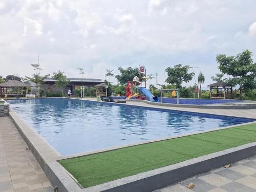 a large swimming pool with a slide and a playground at RedDoorz near Wisata Paribendo Lawang in Lawang