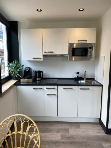a kitchen with white cabinets and a microwave at Boutique Hotel LE•BAR in Zandvoort