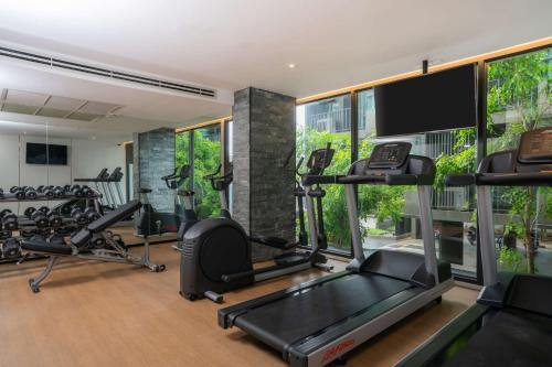 a gym with treadmills elliptical machines and a flat screen tv at Bayphere Hotel Pattaya JC in Na Jomtien