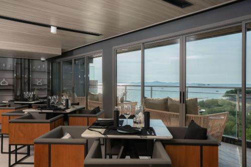 a restaurant with tables and chairs with a view of the ocean at Bayphere Hotel Pattaya JC in Na Jomtien