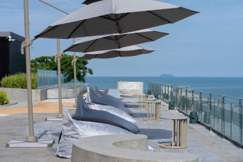 a row of tables with umbrellas on a balcony at Bayphere Hotel Pattaya JC in Na Jomtien