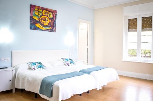 a white bedroom with two beds and a painting on the wall at Hotel Neguri in Getxo