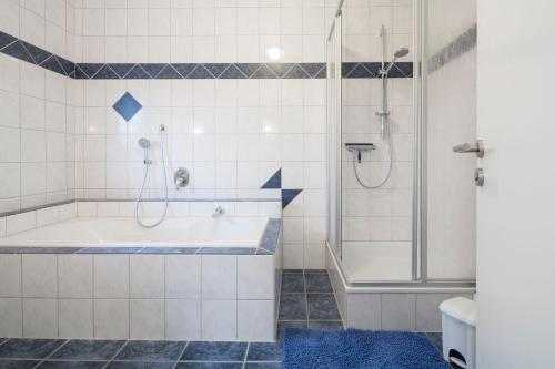 a bathroom with a tub and a shower at Mienhus Apartments Ferienwohnung Fiete in Norden