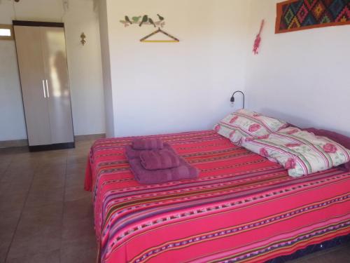 Una cama en una habitación con una manta roja. en El Cardón,habitación privada en el campo en Humahuaca