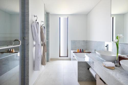 a white bathroom with two sinks and two mirrors at Zulal Wellness Resort by Chiva-Som in Ar Ruʼays