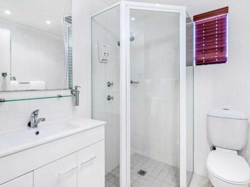 a white bathroom with a shower and a toilet at Country Plaza Motel Taree in Taree