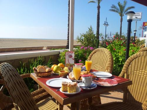 a table with breakfast food and orange juice on a patio at Hotel Bodegón de Peñíscola in Peñíscola