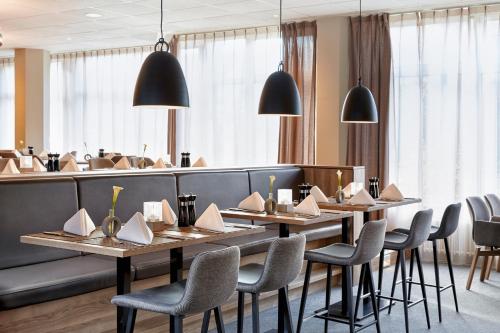 a restaurant with wooden tables and chairs and black booths at H+ Hotel Köln Brühl in Brühl