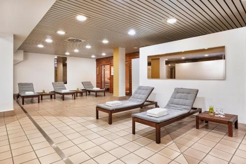 a waiting room with three chairs and a mirror at H+ Hotel Köln Brühl in Brühl