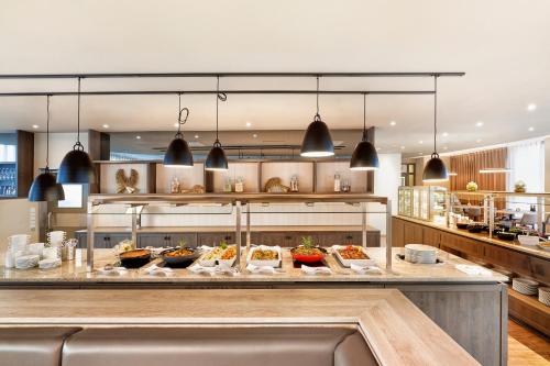 a restaurant with a buffet of food on a counter at H+ Hotel Köln Brühl in Brühl