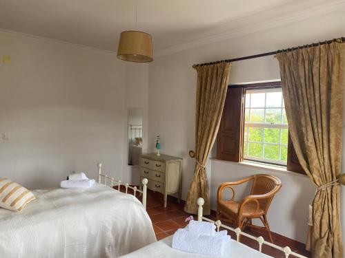 a bedroom with a bed and a chair and a window at Casa da Azinhaga in Alenquer