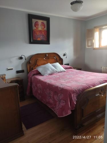 a bedroom with a bed with a pink bedspread at Albergueria Frade in O Cebrero