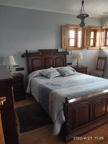 a bedroom with a large wooden bed and two lamps at Albergueria Frade in O Cebrero