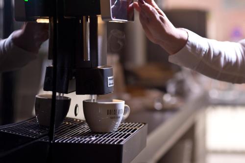 a person is making coffee in a coffee machine at Alevic Hotel Sirmione in Sirmione