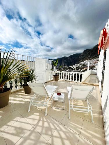 a patio with chairs and a table on a balcony at Luxury penthouse with breathtaking views and huge private terraces in Puerto de Santiago
