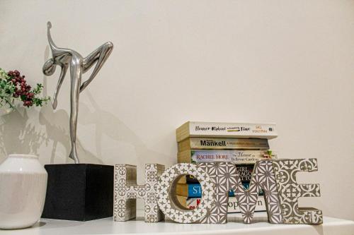 a shelf with a stack of books next to a vase at QLiving Central New Apartments Gzira Sliema Promenade in Il-Gżira