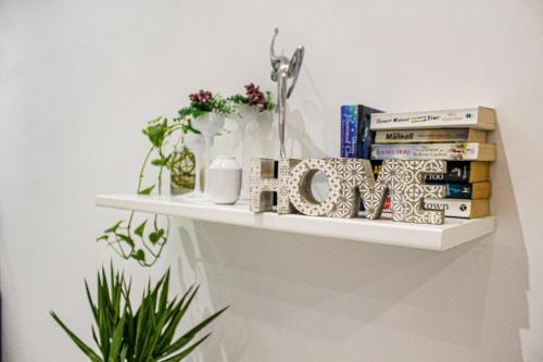 a shelf with books and vases and books at QLiving Central New Apartments Gzira Sliema Promenade in Il-Gżira