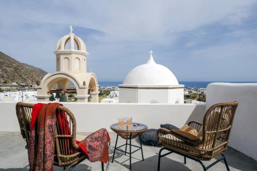 un patio con 2 sillas y una mesa y un edificio en Exi Castle Suites, en Emporio