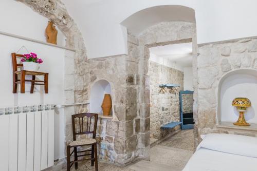 a room with a stone wall and a bed and a chair at Scicli Albergo Diffuso in Scicli