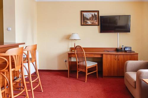 a hotel room with a desk with a television and chairs at Kompleks Antałówka Termy & Med in Zakopane
