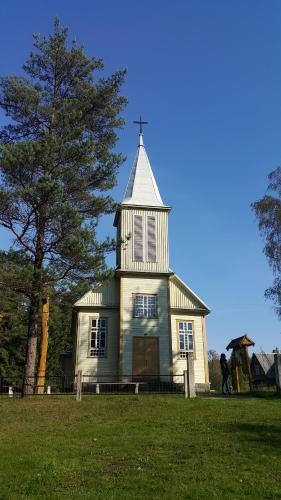 a church with a cross on top of a field at Amatų kalnelis in Anykščiai