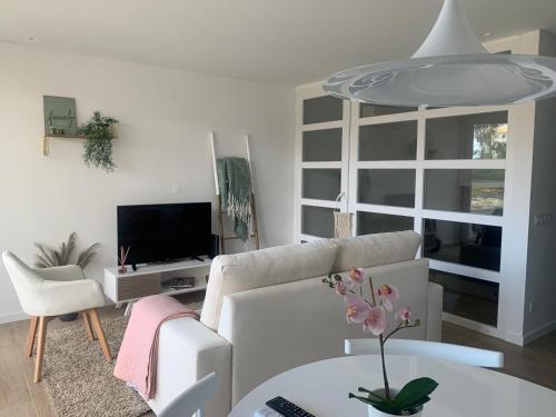 een woonkamer met een witte bank en een tv bij Golden Coast Residence in Portimão