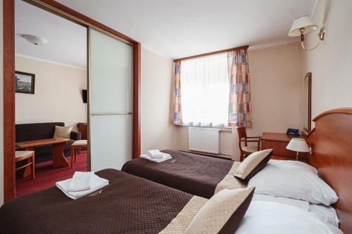 a hotel room with two beds and a mirror at Kompleks Antałówka Termy & Med in Zakopane