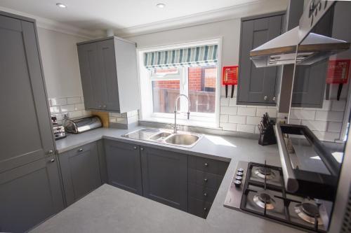 a kitchen with gray cabinets and a sink and a window at The Lakes Rookley in Rookley