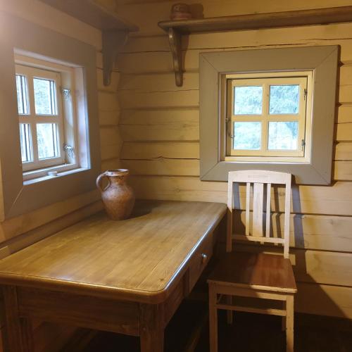 a wooden bench in a room with two windows at Amatų kalnelis in Anykščiai